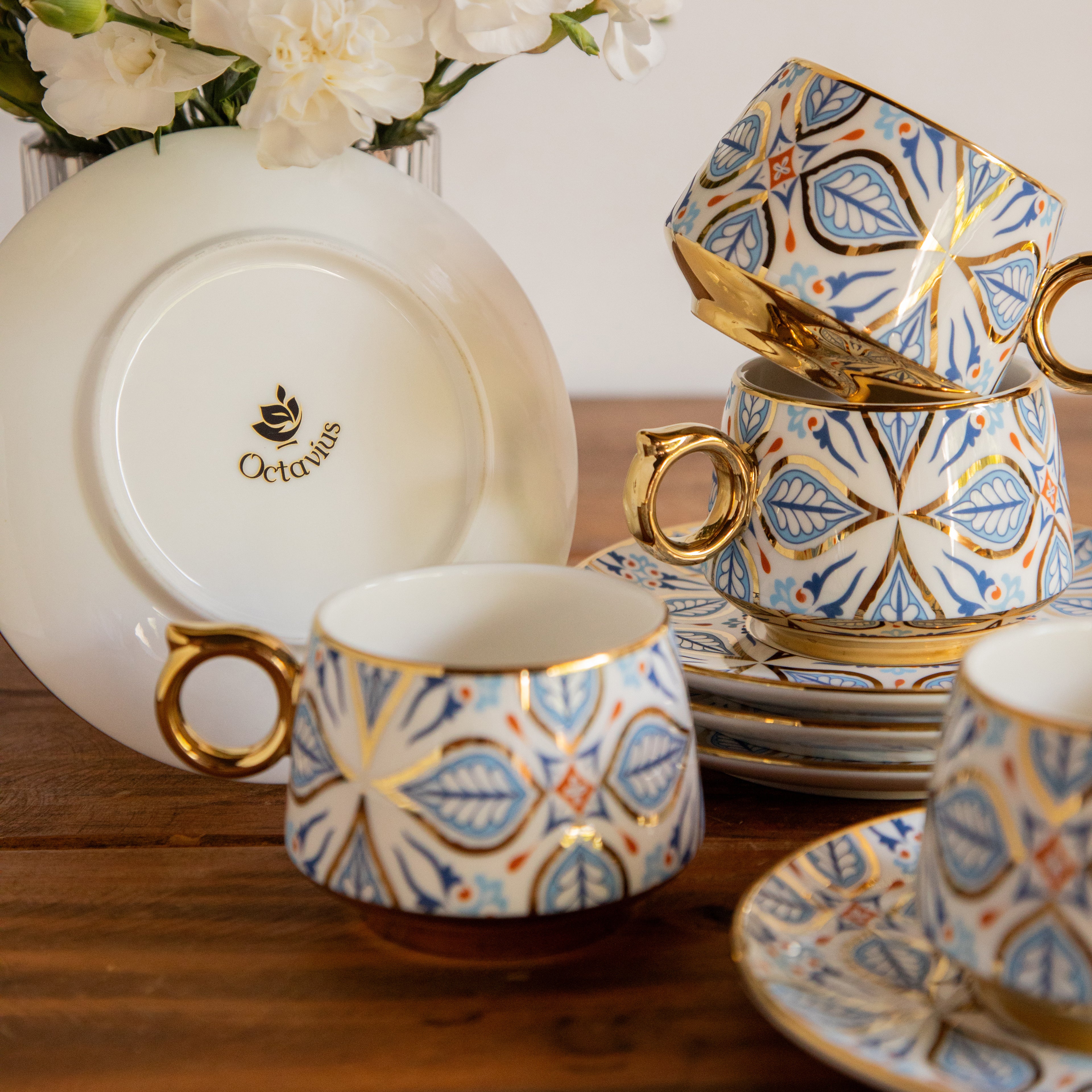 Decorative tea set with patterned cups and saucers on a wooden surface.